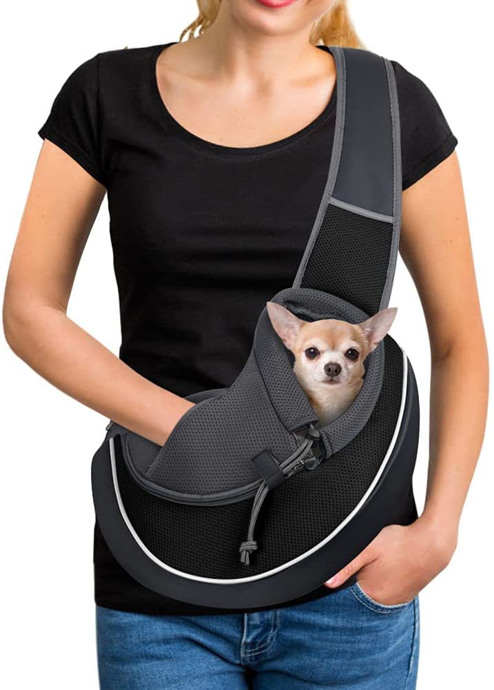 A portable crossbody pet bag being modeled by a woman with a small dog inside